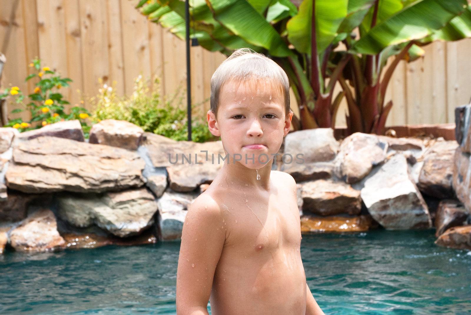 Young boy after getting out of swimming pool dripping wet.