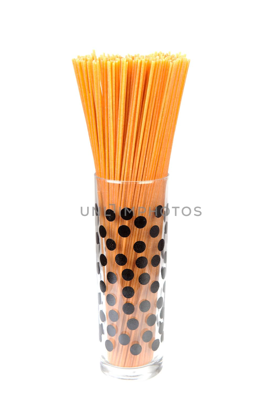 bundle of raw spaghetti in dotted glass over white background