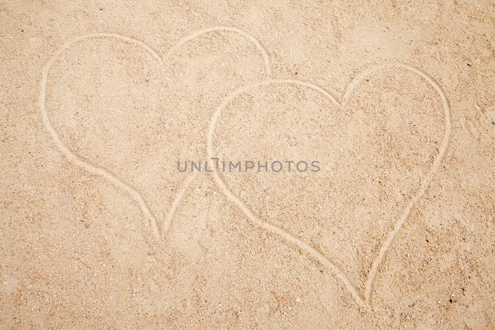 two hearts drawn in sand in closeup