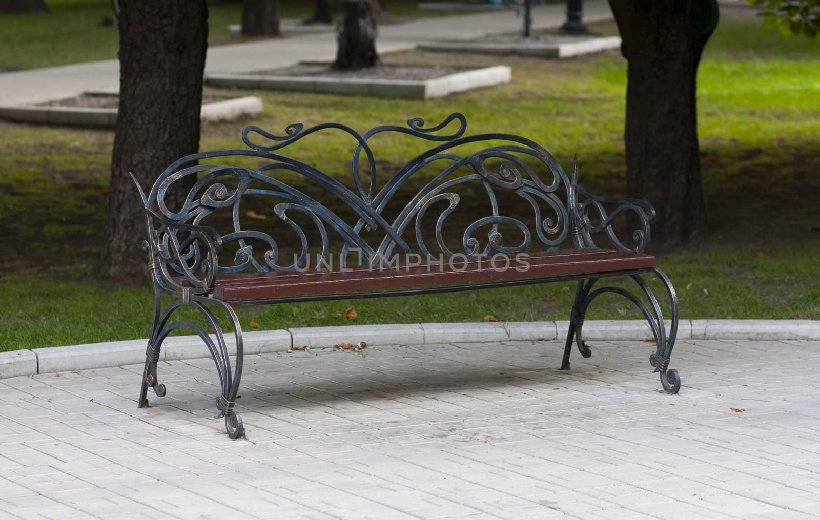 Metal forged bench in summer park with abstraction curles