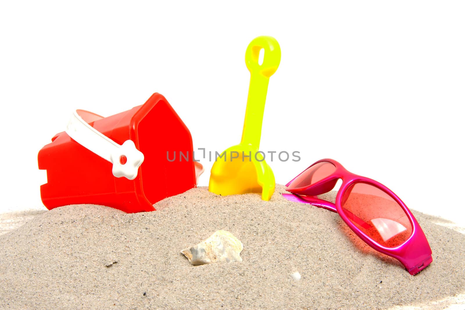pink sunglasses and beach toys over white background
