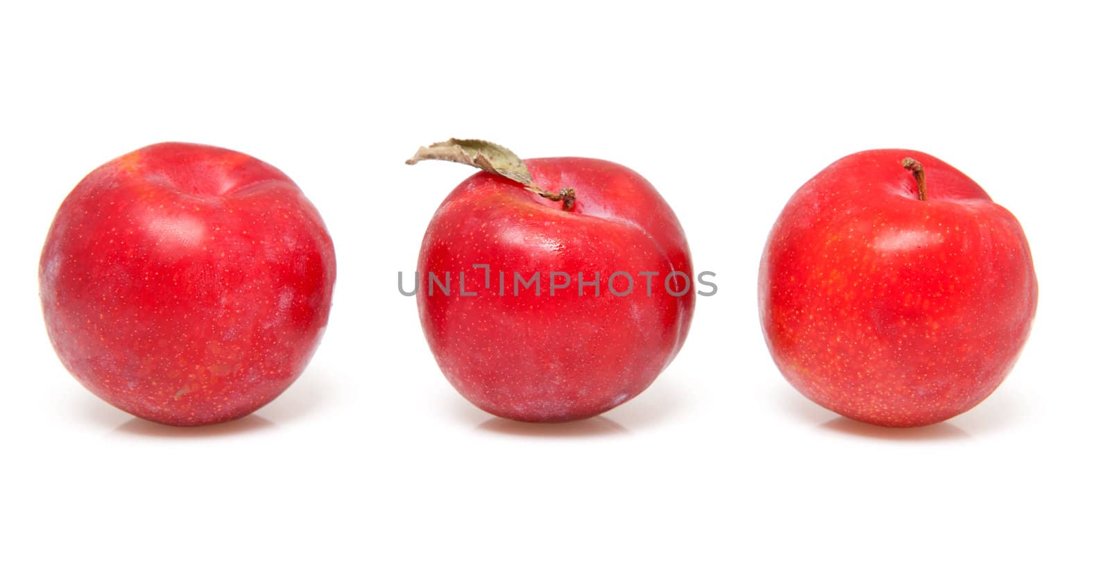 three red plums in a row over white background