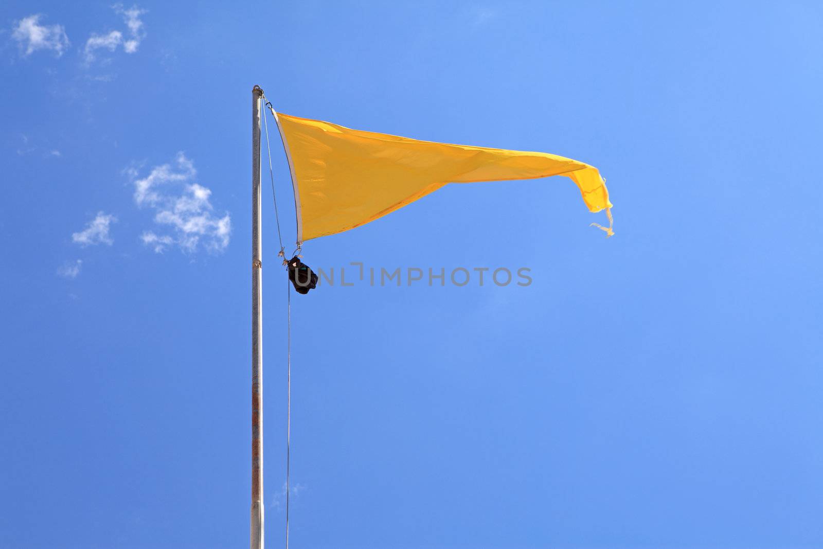 yellow warning flag on the beach against blue sky