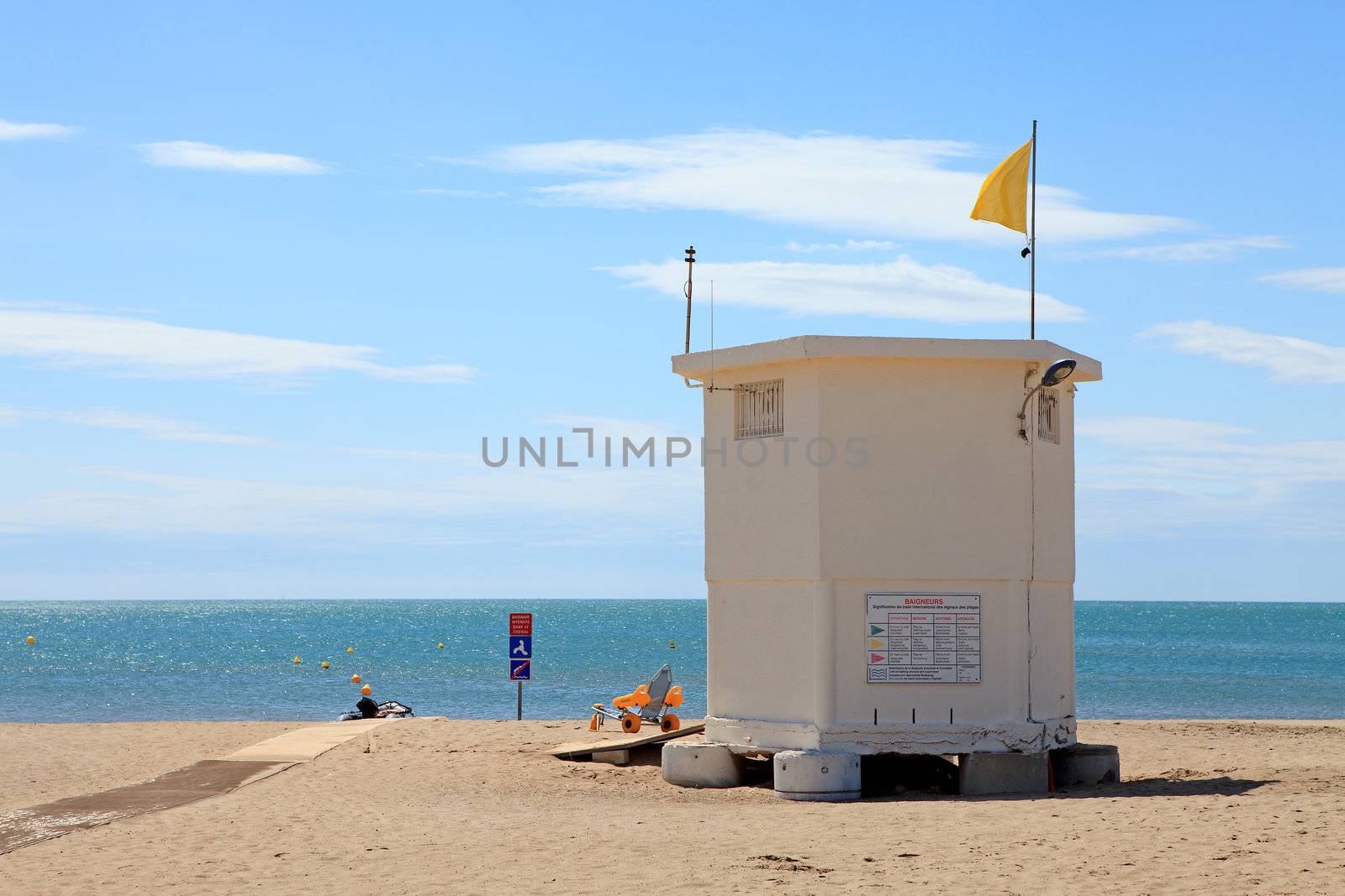 lifeguard hut at the beach with yellow flag on sunny day