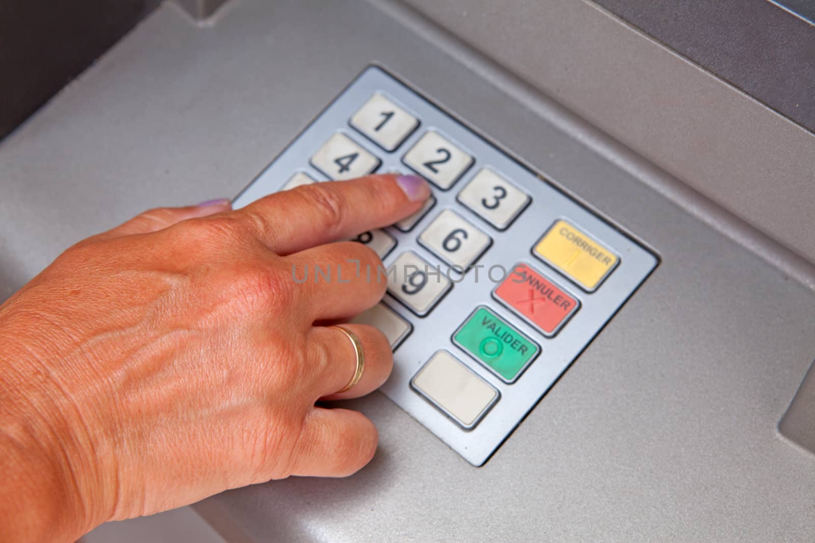 Hand is entering personal identification number on ATM dial panel
