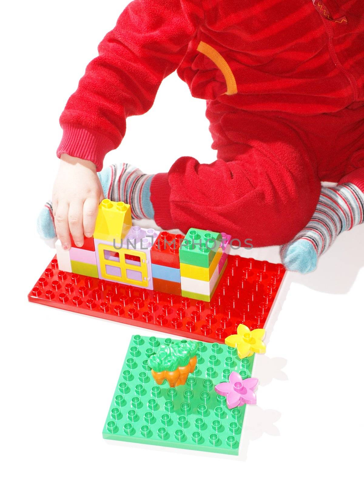 Unrecognizable kid in red, playing with colorful plastic quick build toys