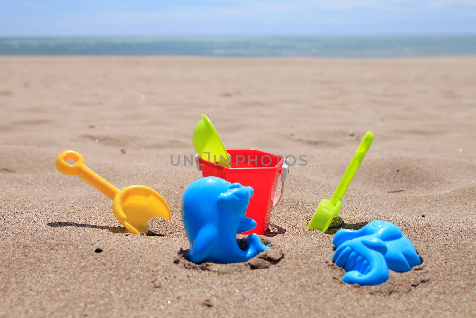 colorful plastic beach toys in the sand near the ocean