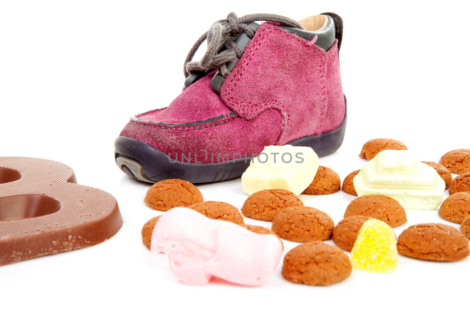 purple little children's shoe with chocolate letter and pepernoten ( ginger nuts), traditional for Sinterklaas in the Netherlands over white background
