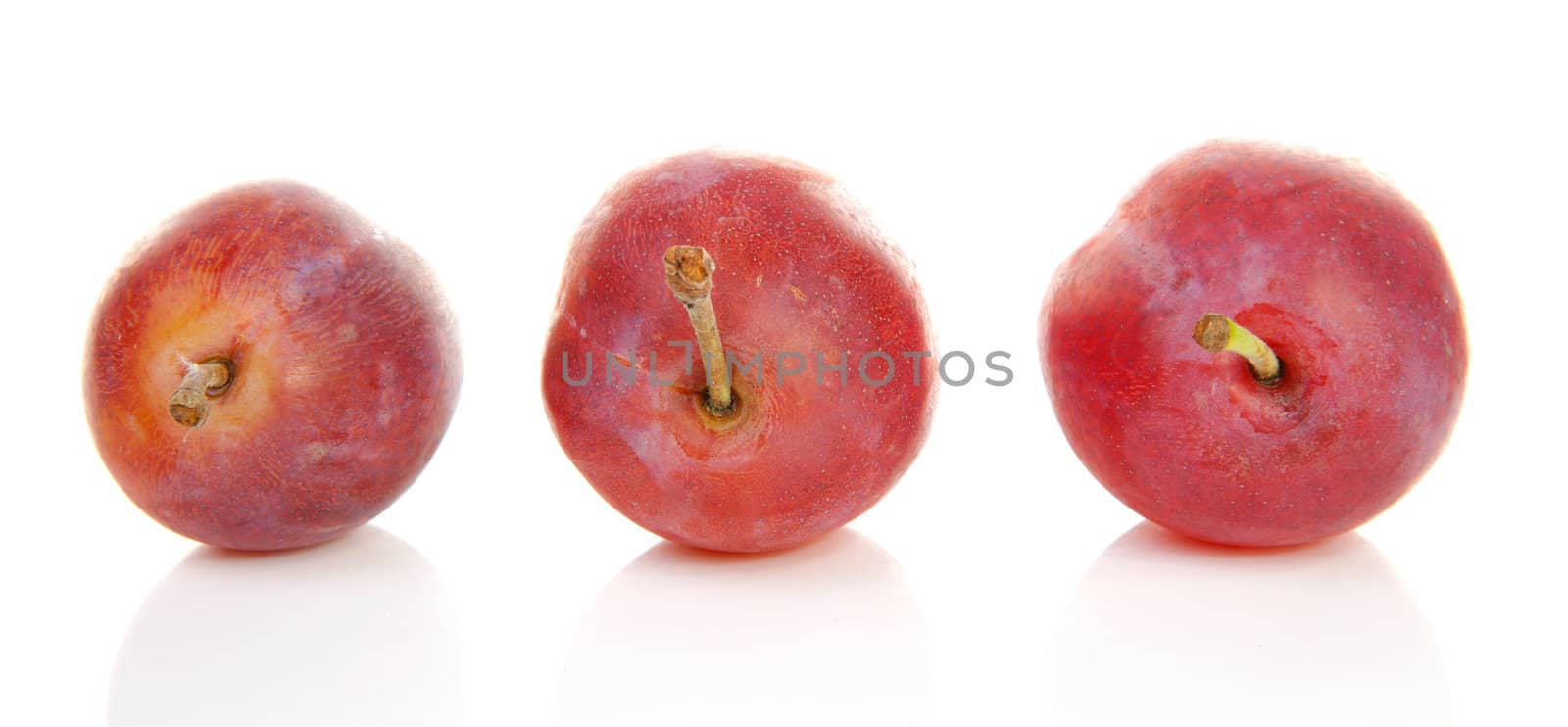 Three healthy plums over white background