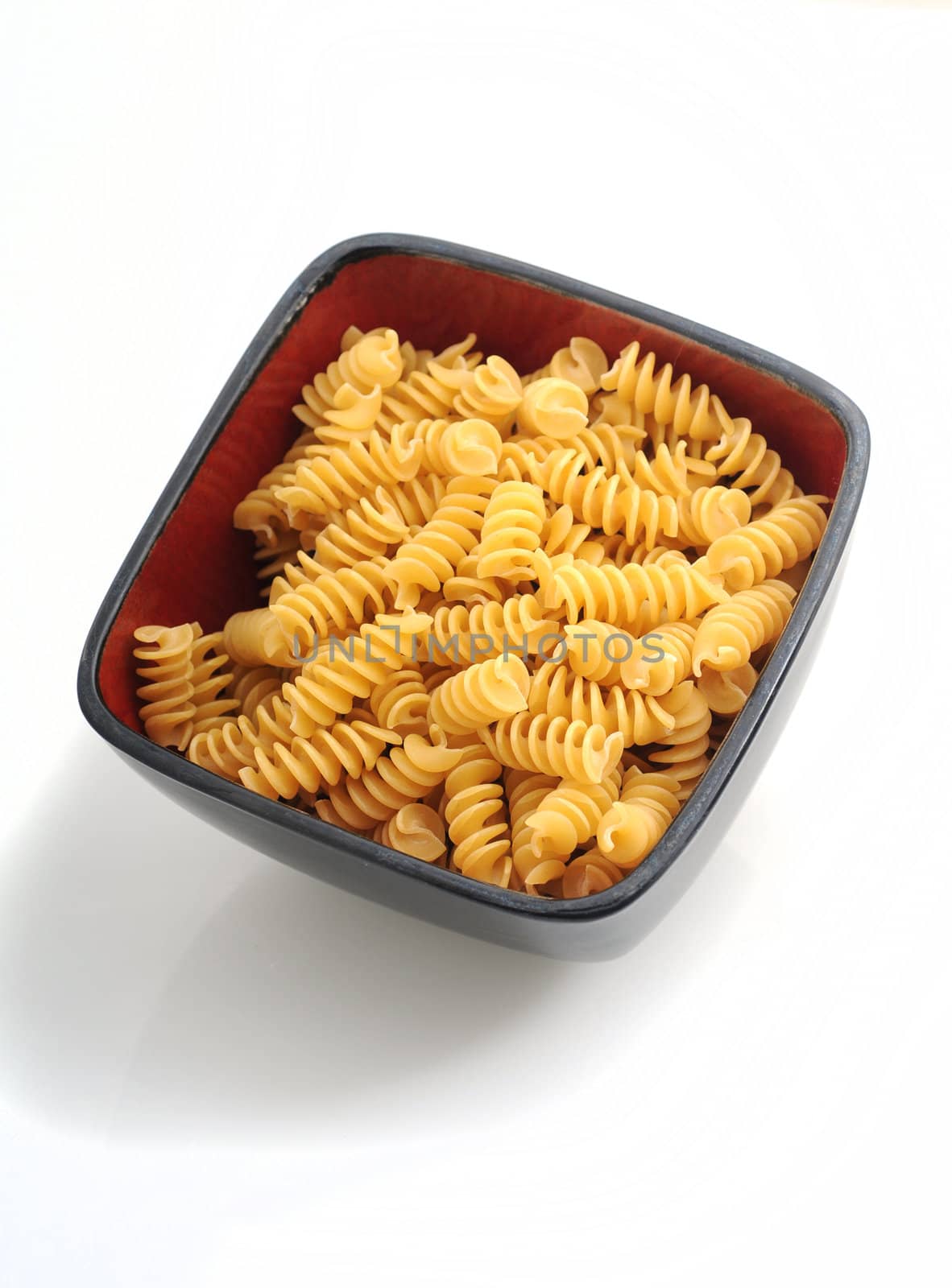 a bowl of rotellii pasta in red bowl on white background