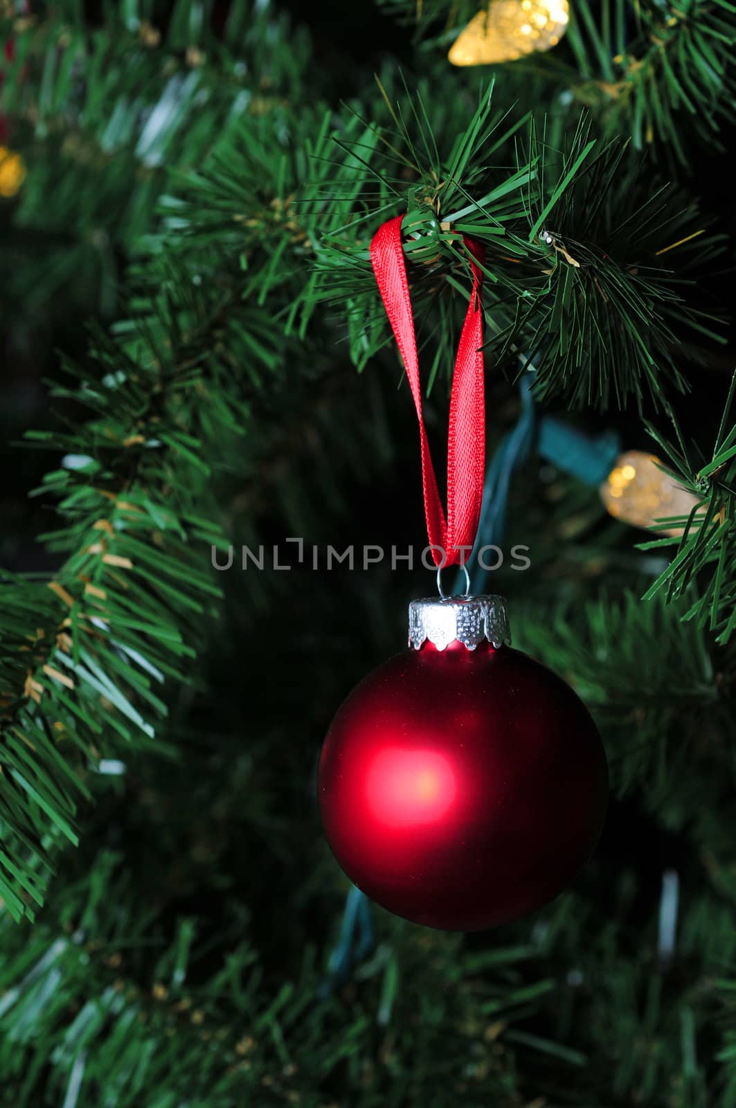 matte red christmas ornament hanging on tree with lights