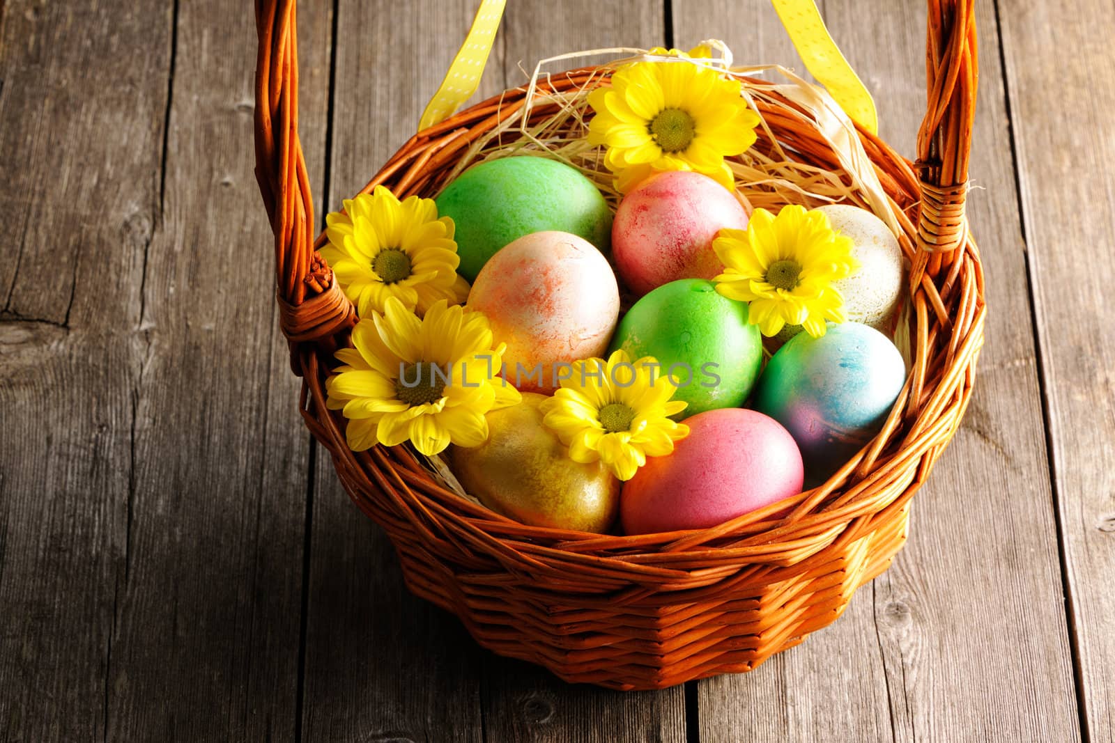 Colored easter eggs in basket on wooden table