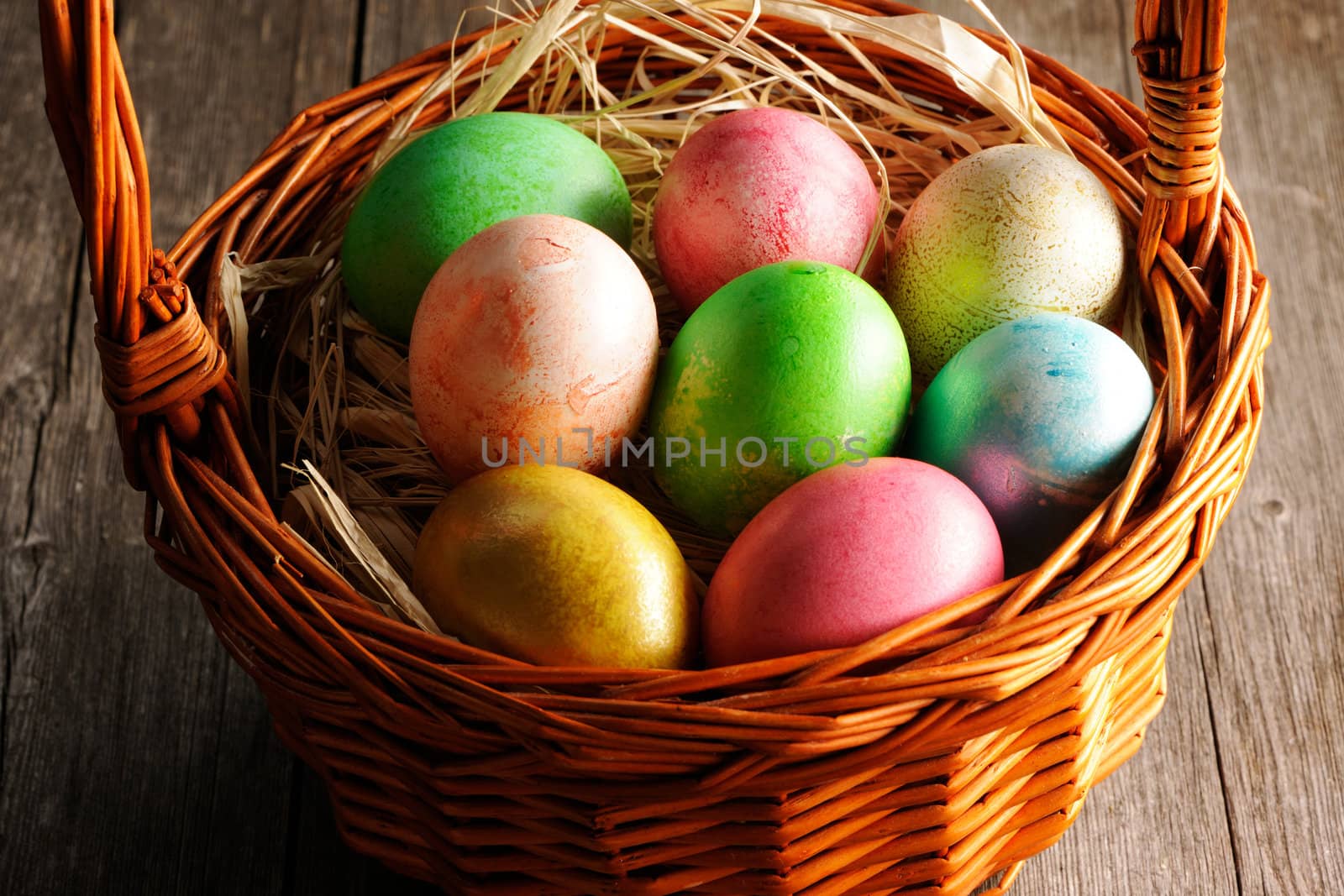 Colored easter eggs in basket on wooden table