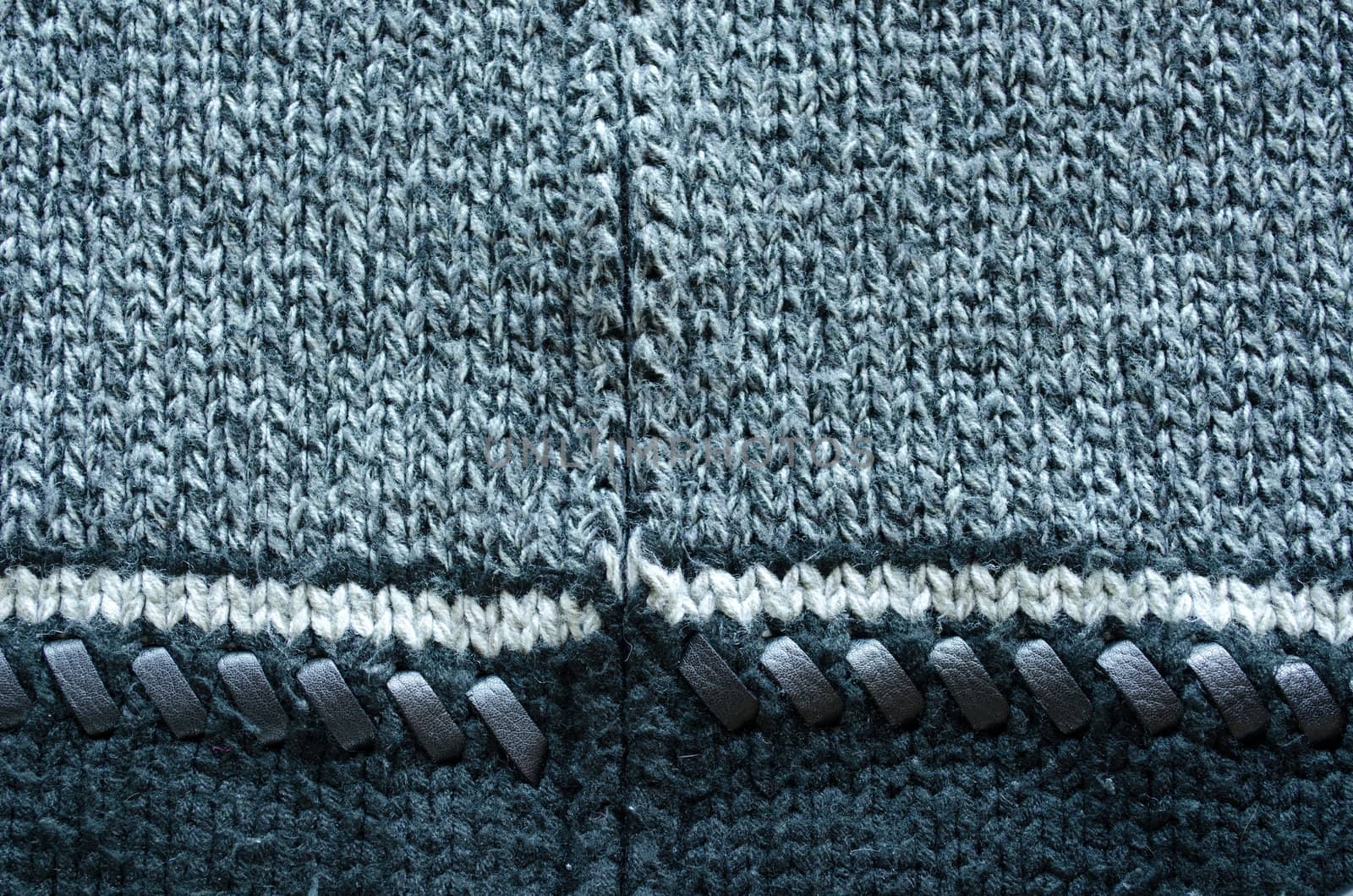 wool knit sweater texture decorated with leather stitch. white grey and black colors backdrop closeup