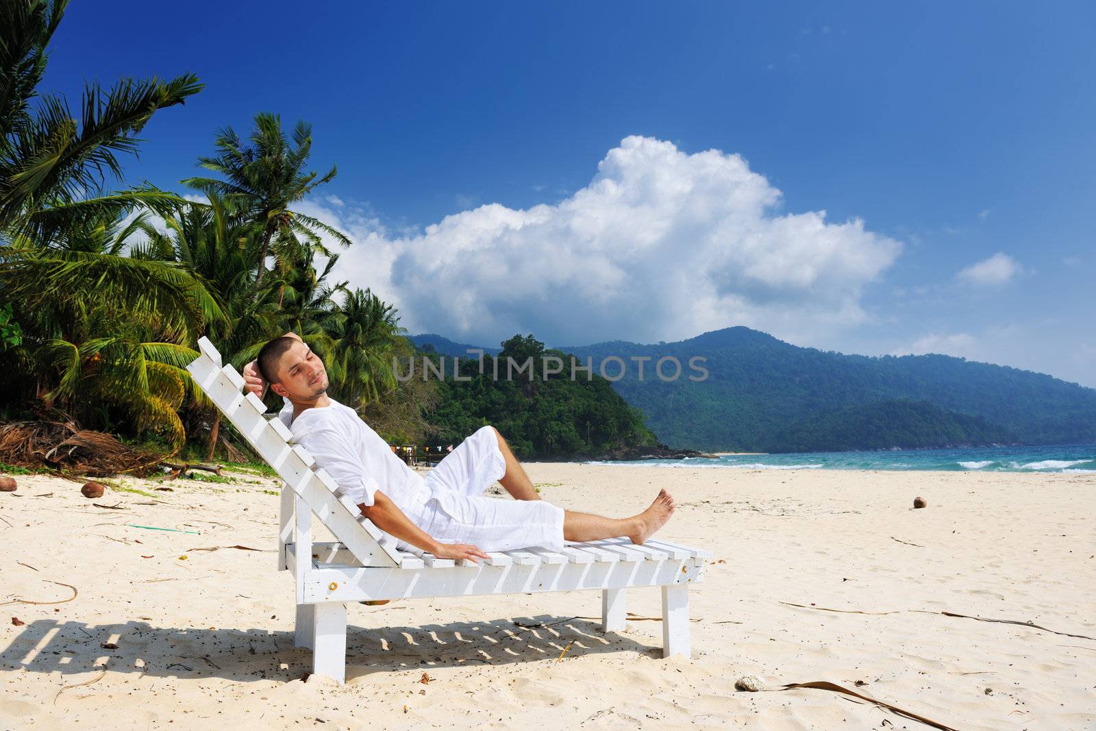 Man in white relaxing on a tropical beach