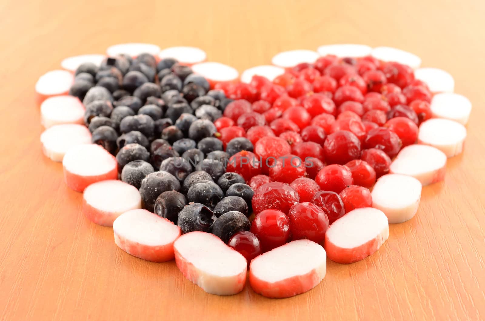 Frozen cranberries and  blackberry are laid out in the form of heart close-up