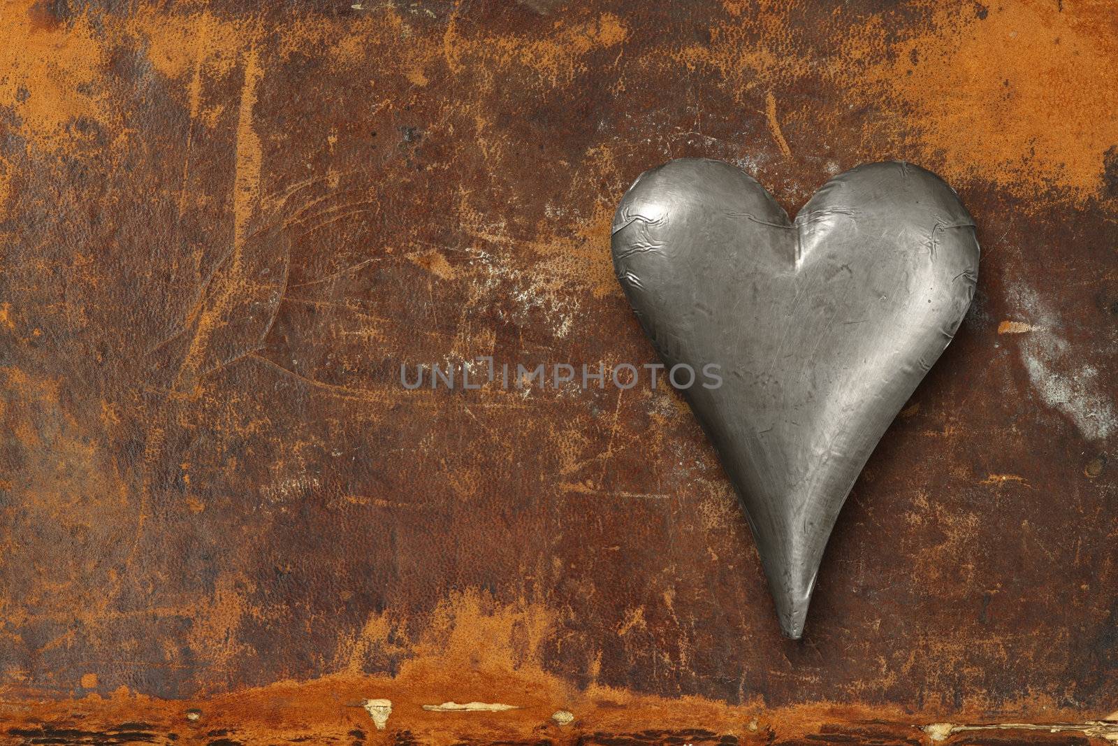 Photo of a metal heart sitting on an old leather book cover.
