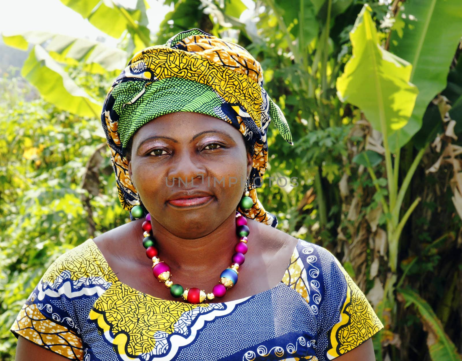 Portrait of a beautiful middle-aged black African woman, wearing traditional clothing or boubou with scarf in bold graphic pattern.