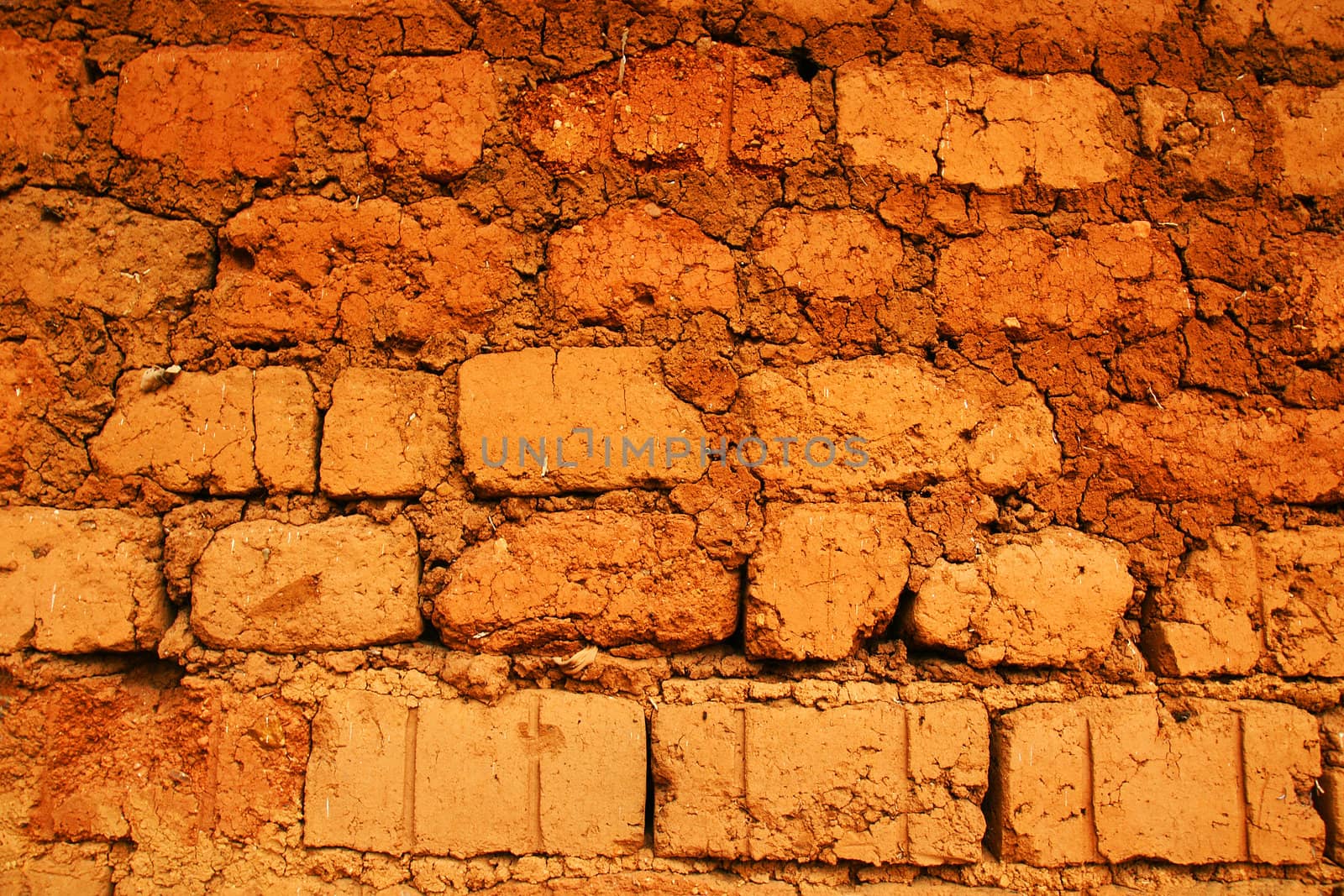 Wall of a house in red clay, earth or soil bricks, great texture background, poverty, developing or tropical country concept.