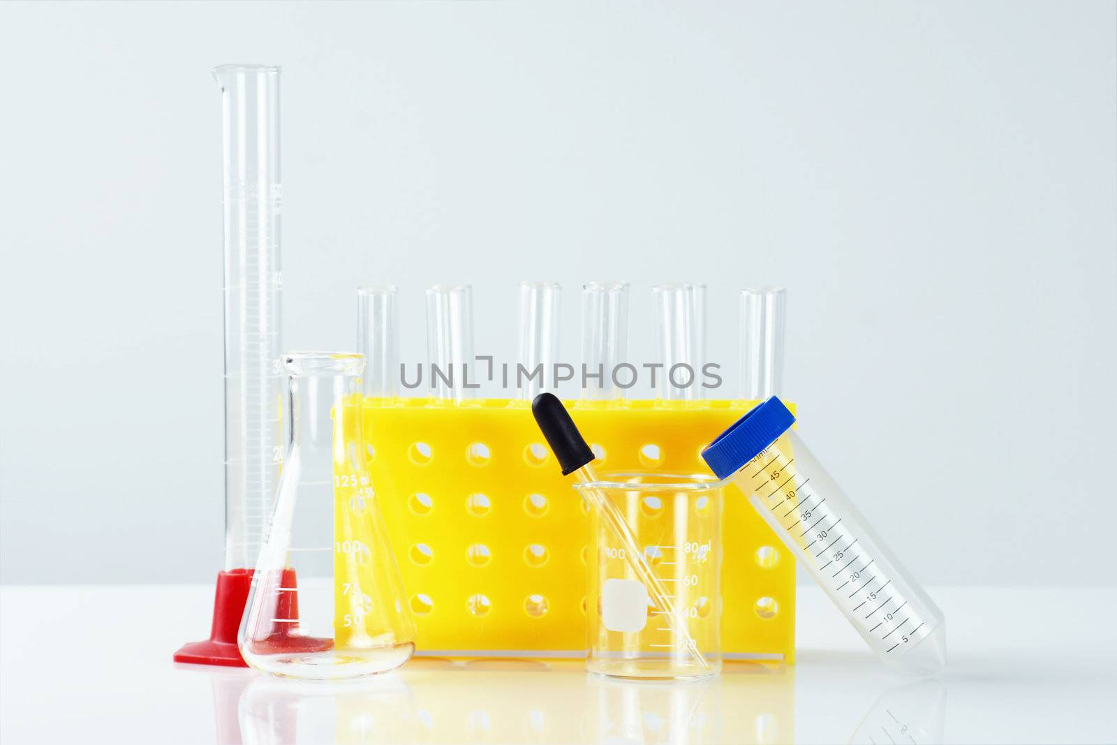 Science, research or chemistry concept: empty laboratory glassware, with yellow test tube rack, beaker, graduated cylinder and others.