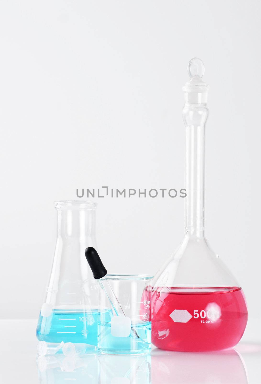 Vertical studio shot of laboratory glassware, with blue and pink color liquids, great science background.