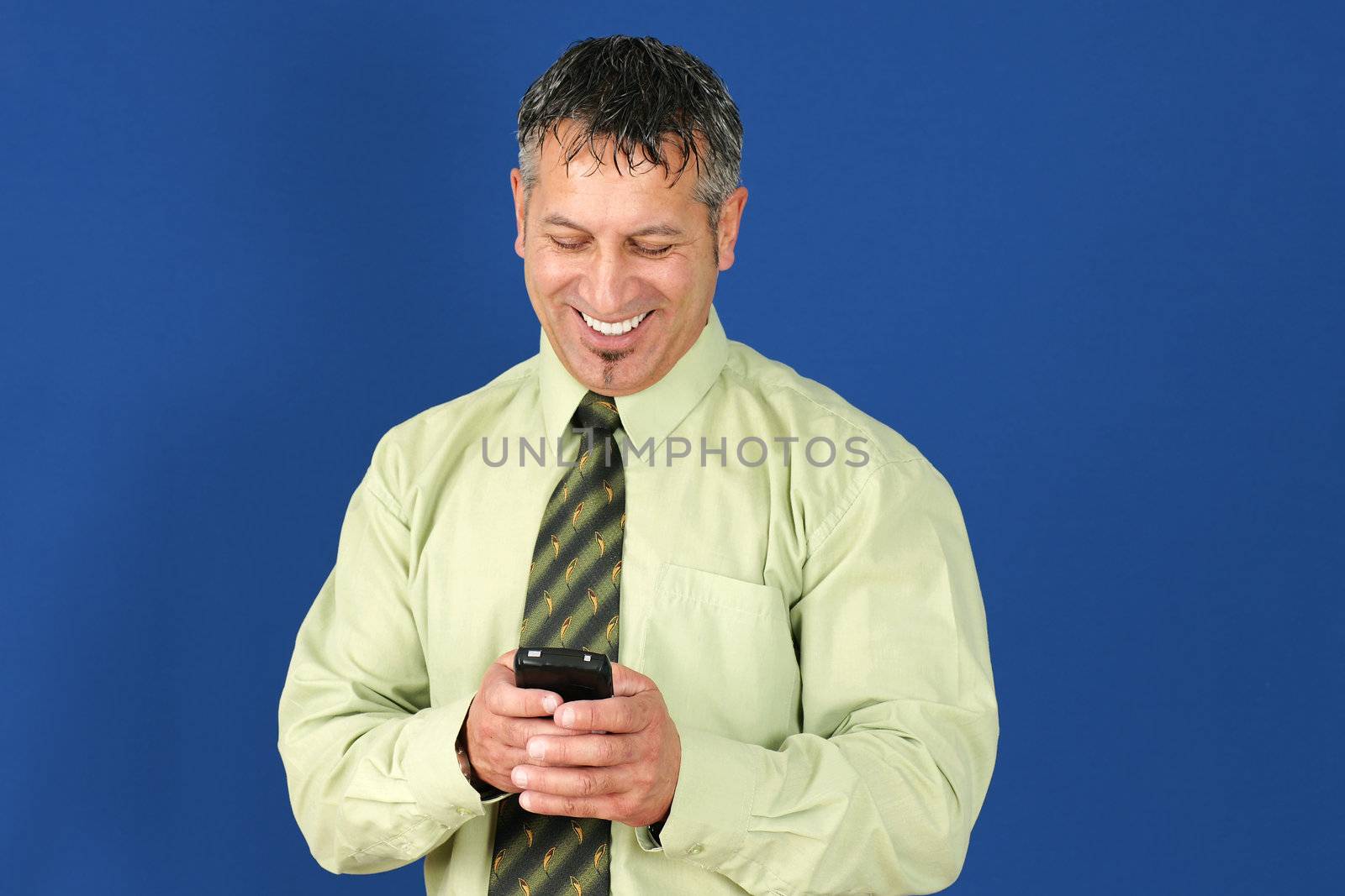 Happy and smiling middle aged man or businessman, with salt and pepper hair, reading or texting message on his smart cell phone or mobile.