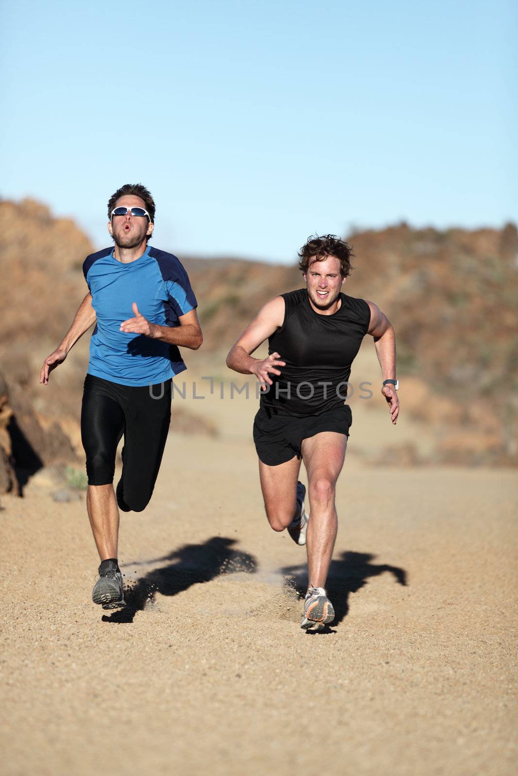 Runners. Men sprinting outdoor in extreme desert nature landscape. Two male athletes running training outside off trail.