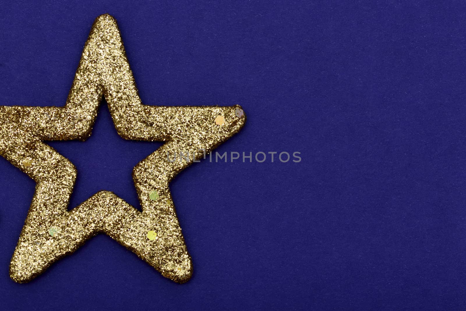 Golden glittering star Christmas ornament isolated on a blue background