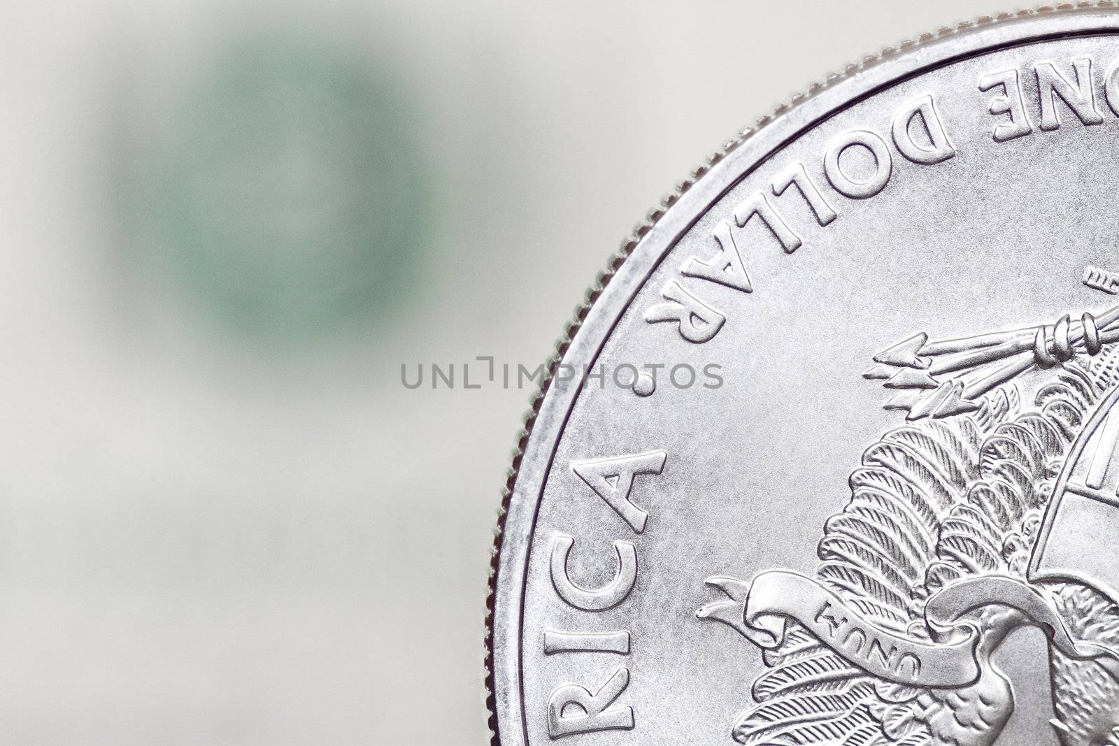 Silver shiny one dollar coin on a blurry background of dollar bill