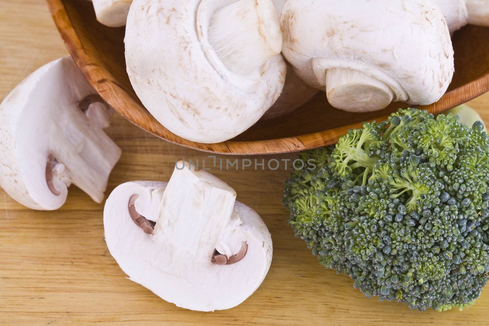 Fresh mushrooms and broccoli in the wooden cutting board