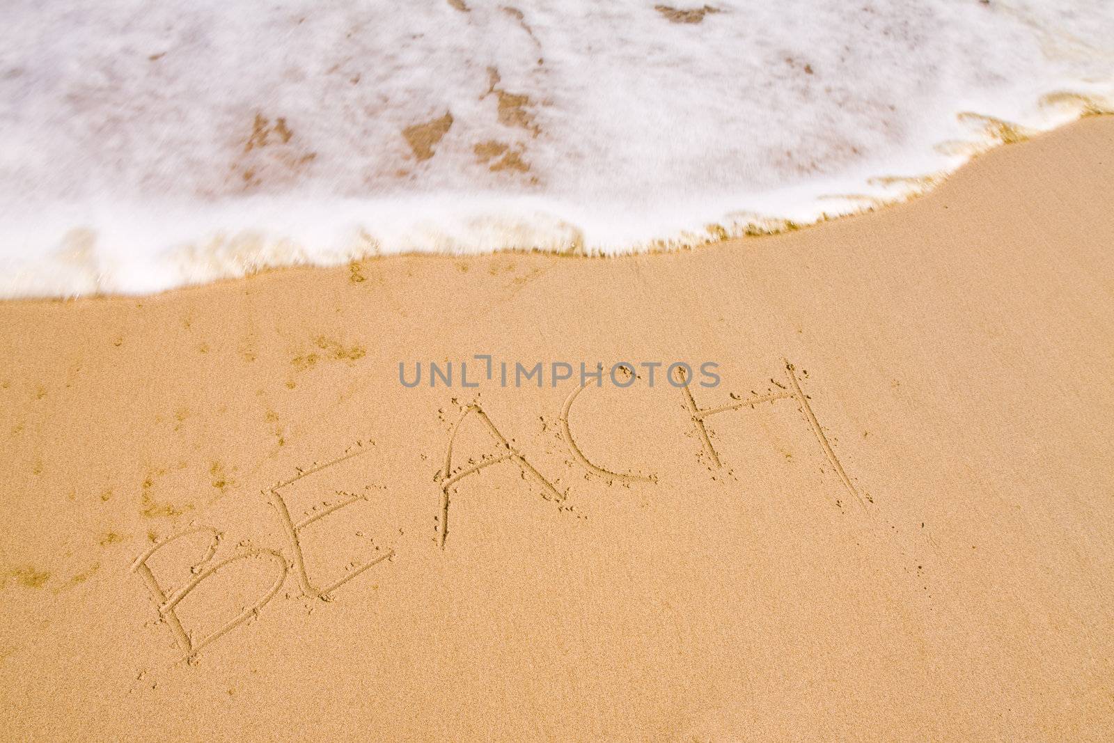 The word beach written with the finger in the sand, seashore