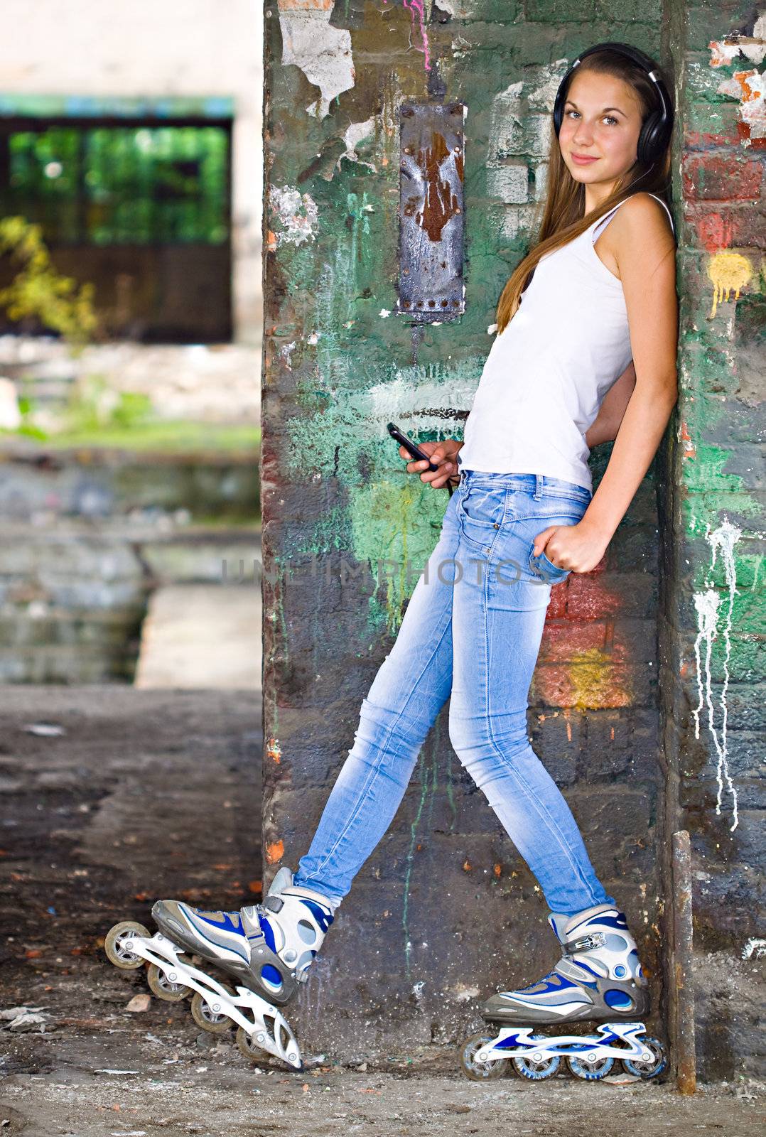 Young girl with headphones and roller shoes at painted wall