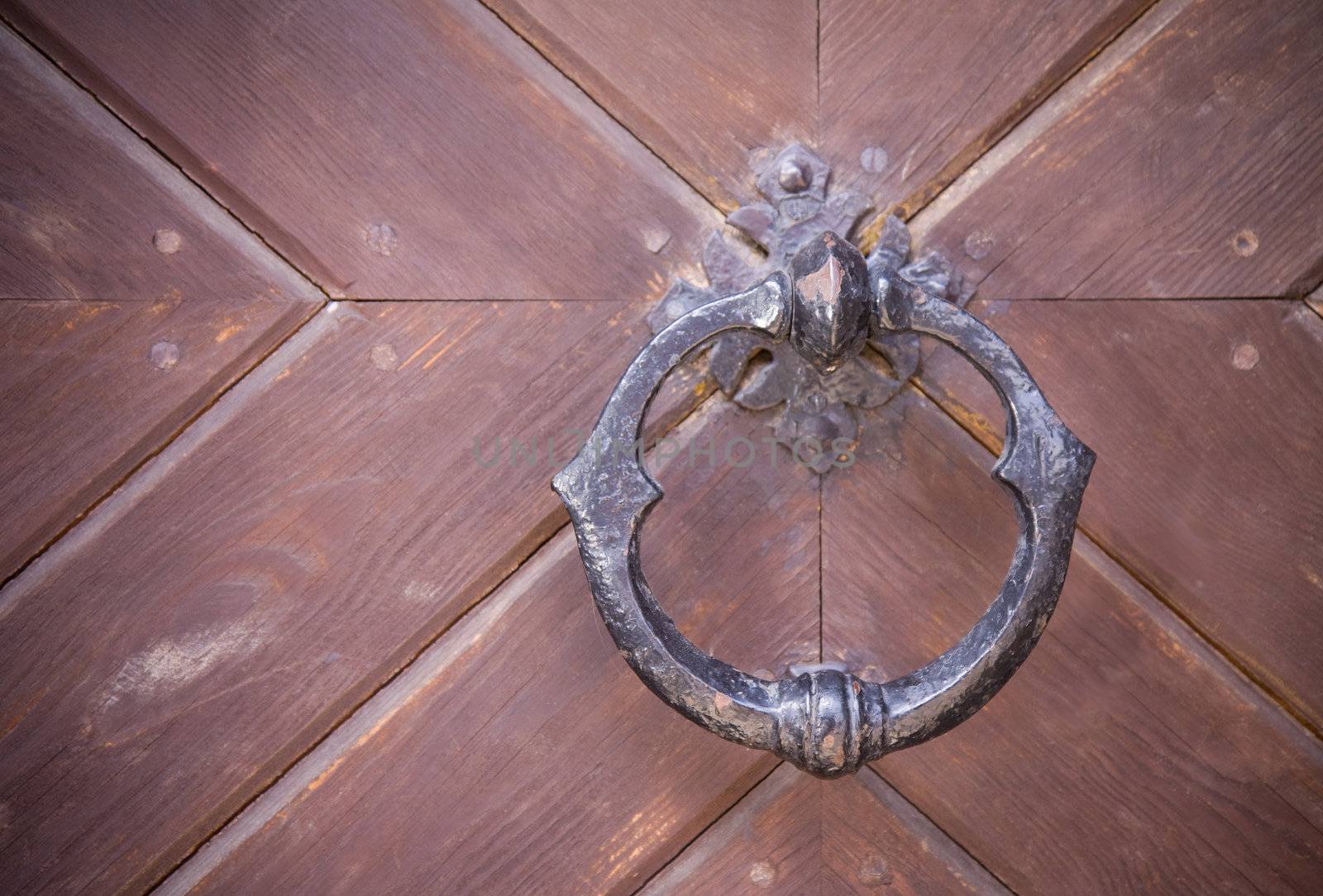Steel medieval knocker on the old wooden door