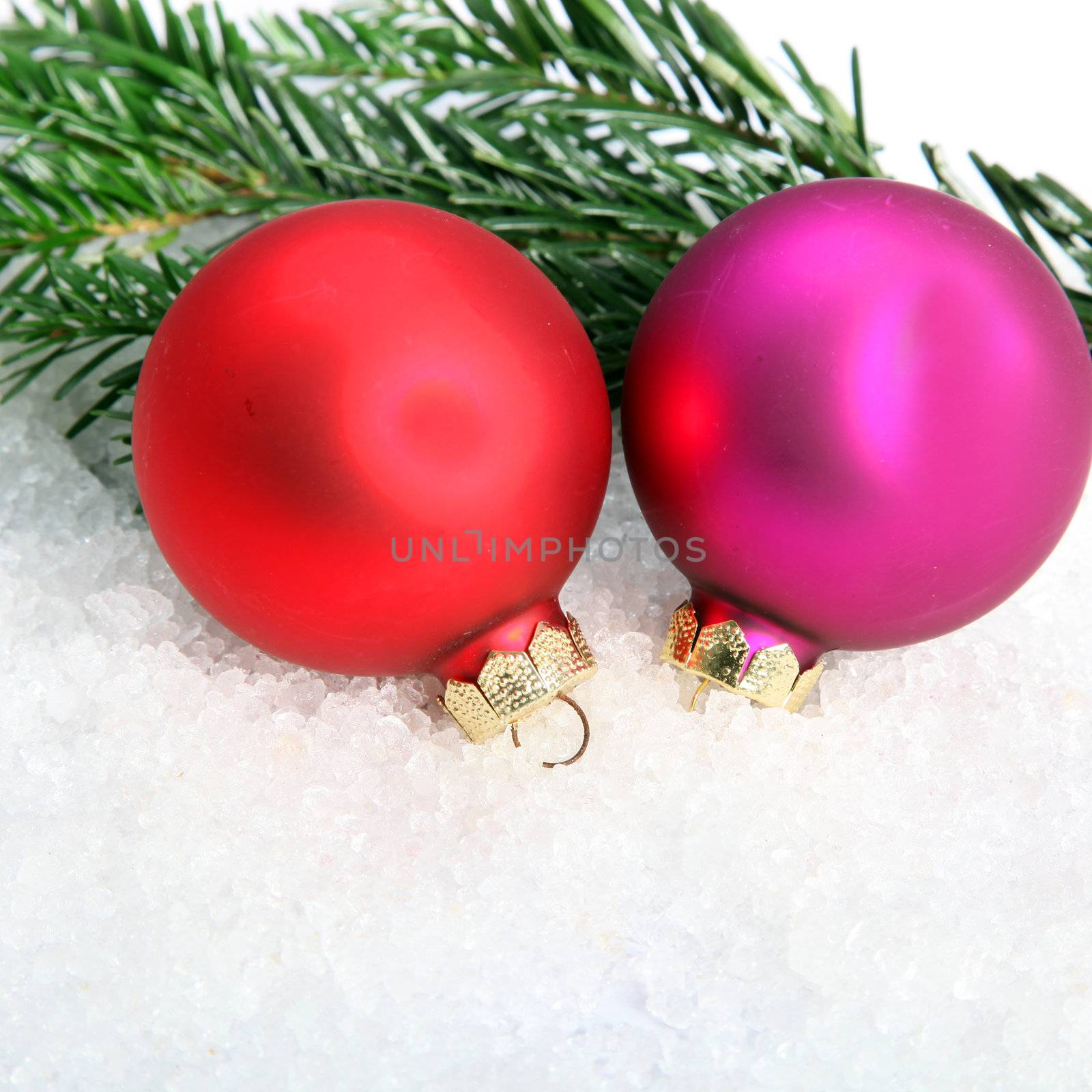 Two colorful Christmas baubles and pine needles on snow