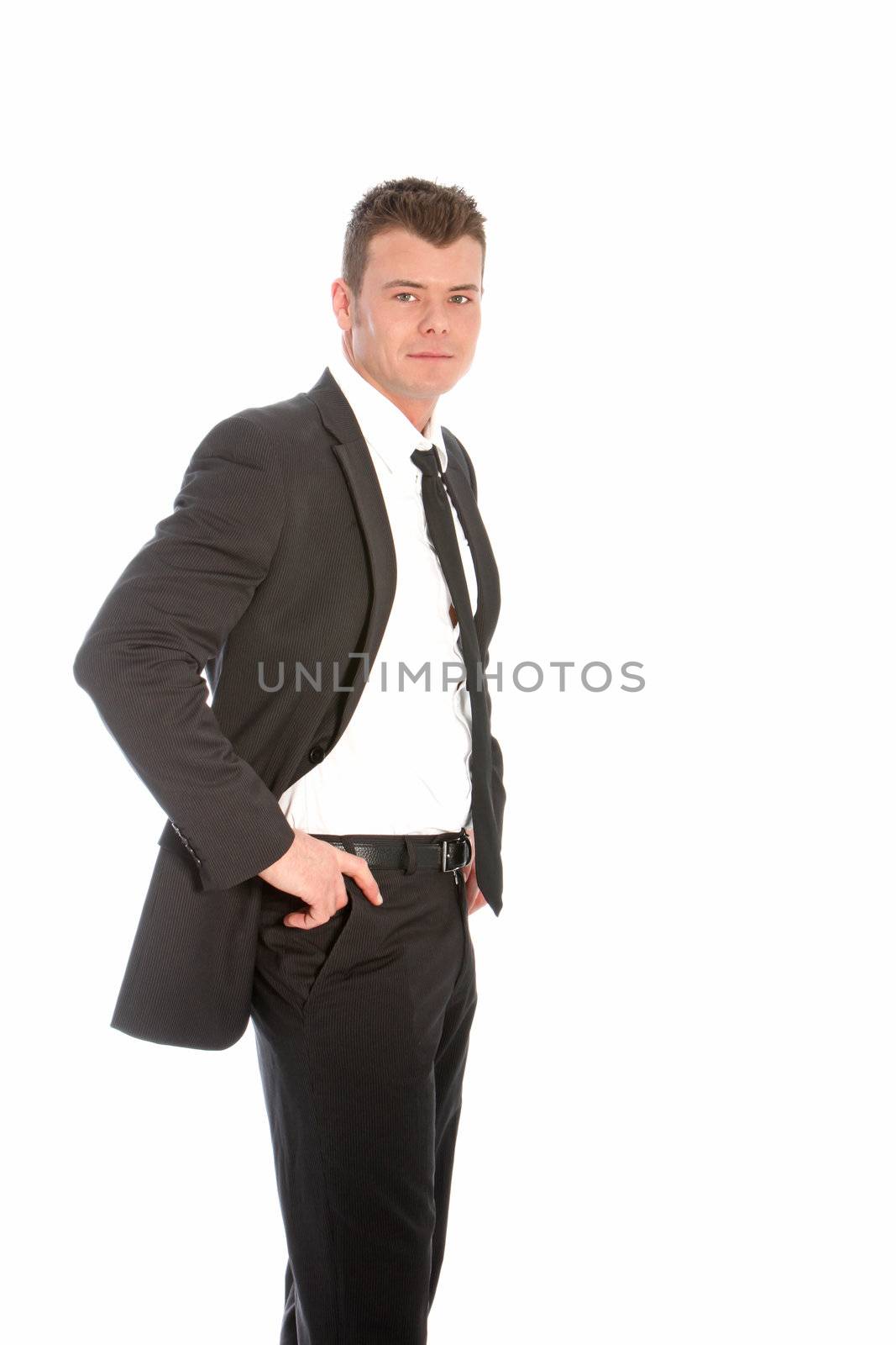 Handsome confident businessman standing in a relaxed manner with his jacket unbuttoned and hands on his hips isolated on white