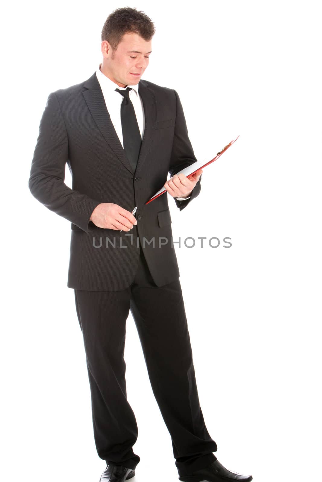 Full length studio portrait of a handsome young businessman in a stylish suit standing reading notes on a clipboard isolated on white