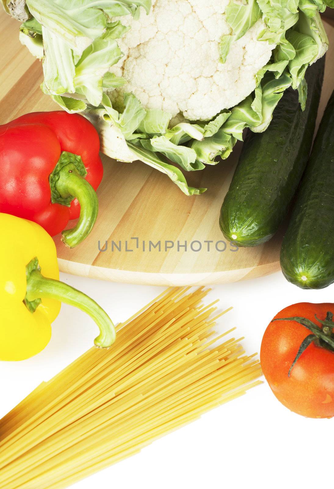 Vegetables (pepper, tomato, caulflower, cucumber) and spaghetti over white background