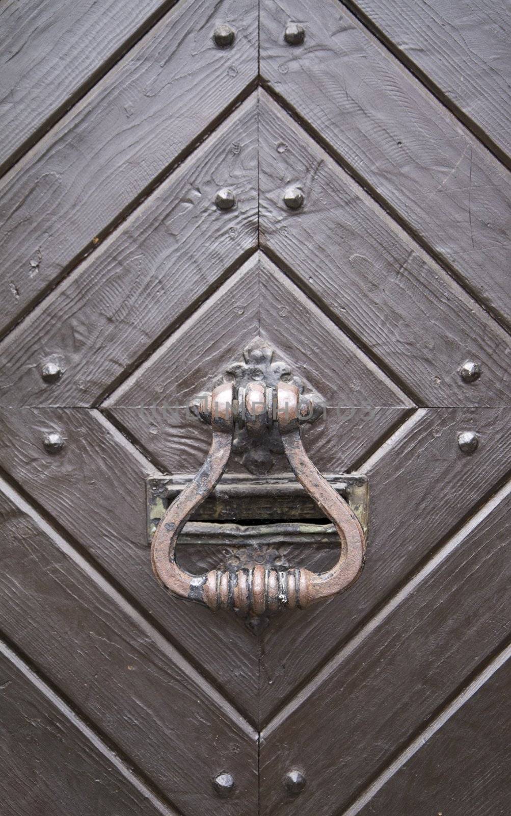 Steel medieval knocker on the old wooden historic door