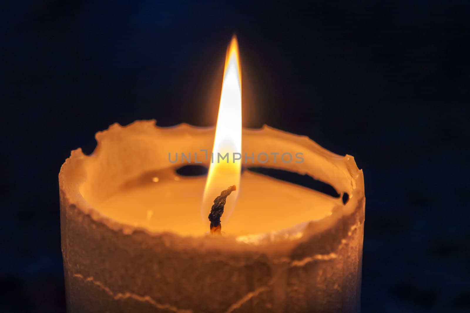 Macro of a beautiful glowing burning candle in the darkness