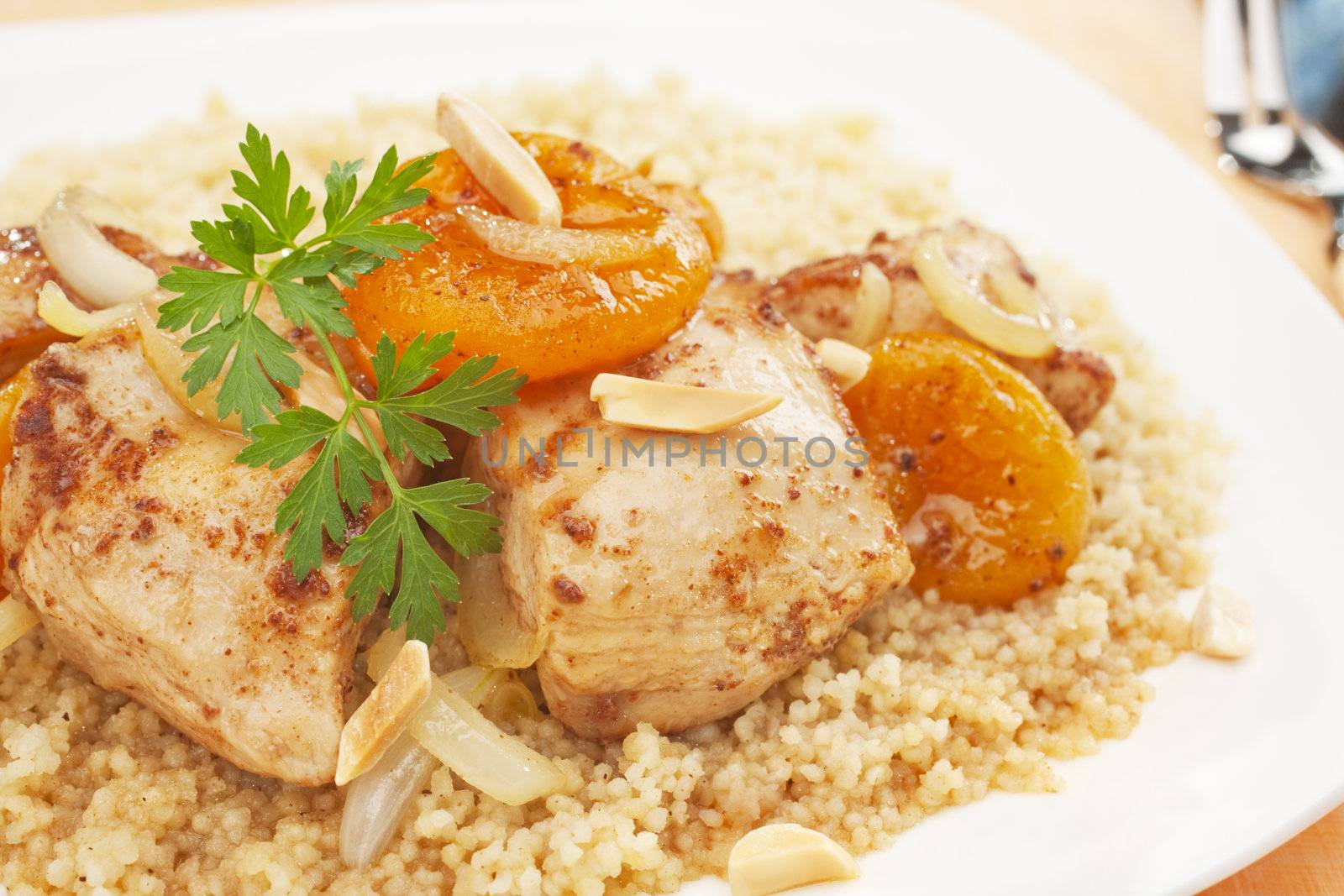 A Moroccan dish, chicken and apricot tajine served over couscous. Tagine is flavoured with ginger, cinnamon, chili and honey.