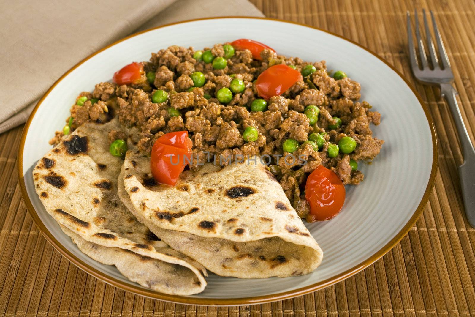Plated meal of lamb keema matar with chapatis.