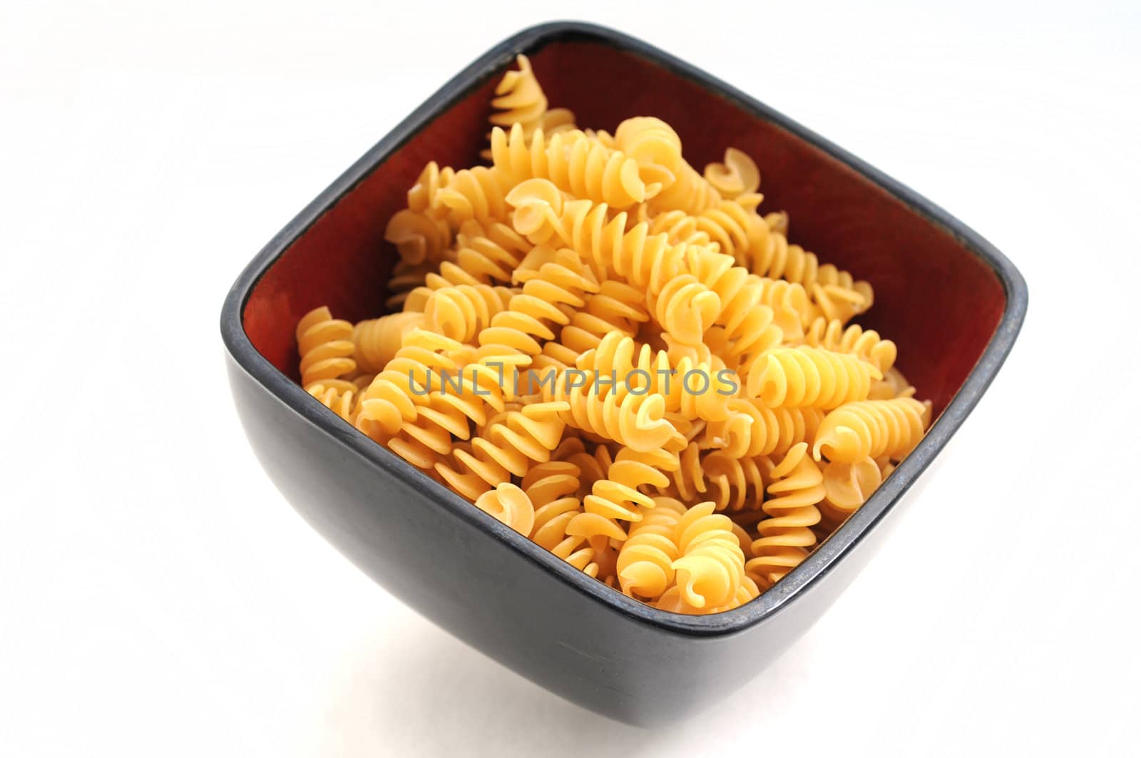 Rotelli pasta in red bowl on white background