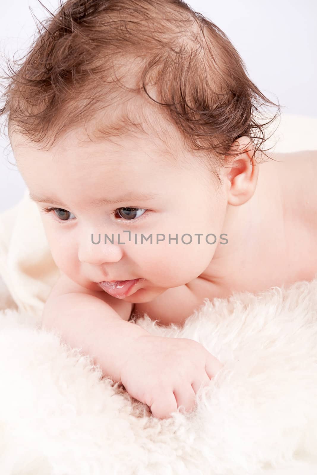 cute little baby infant toddler lying on white blanket smiling portrait