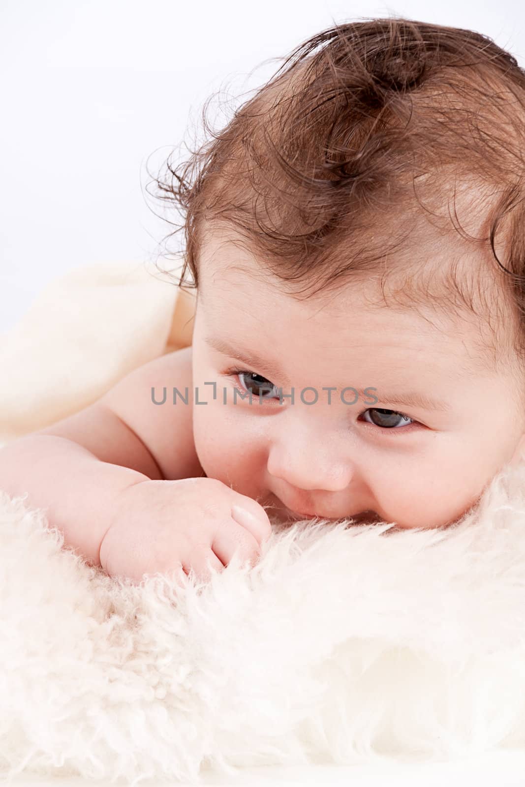 cute little baby infant toddler lying on white blanket smiling portrait