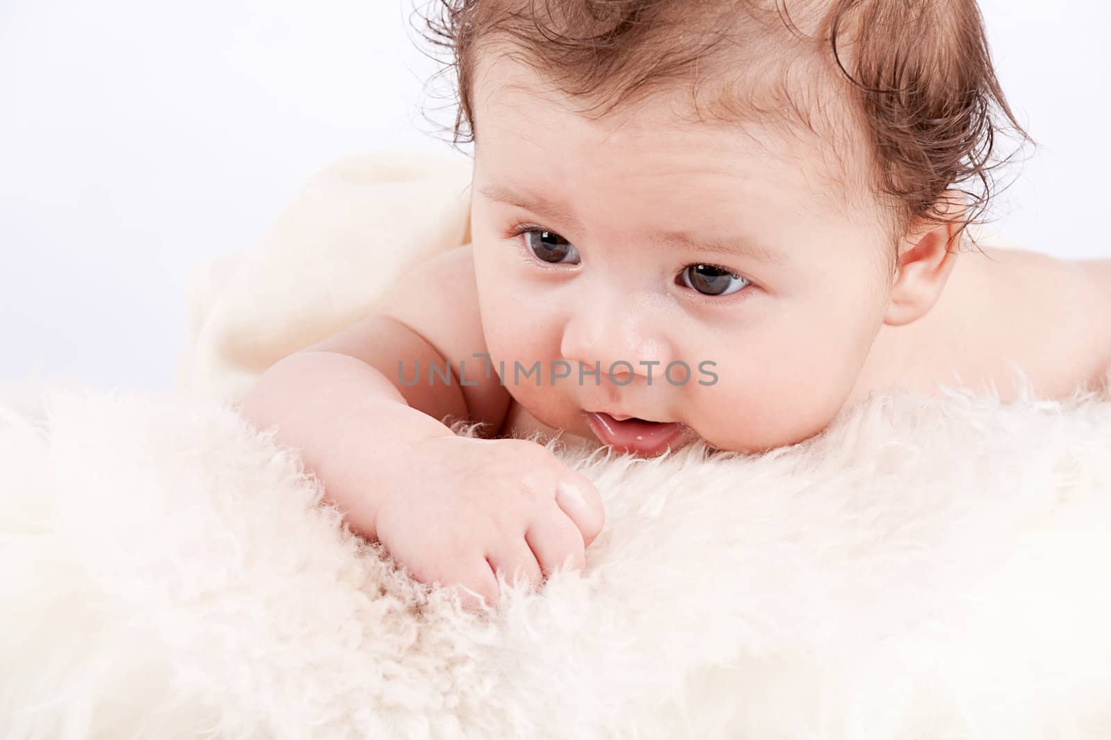 cute little baby infant toddler lying on white blanket smiling portrait