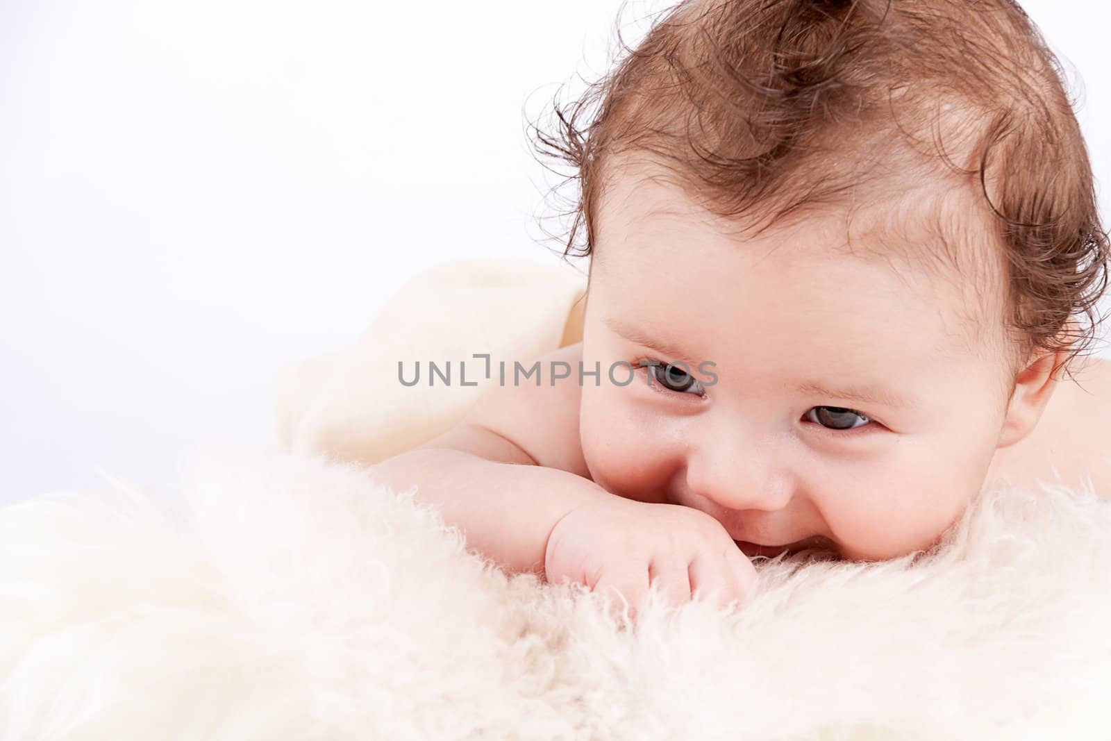 cute little baby infant toddler lying on white blanket smiling portrait