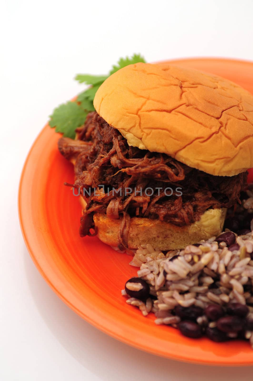 Barbecue beef sandwich with beans and rice for a hearty dinner on an orange plate