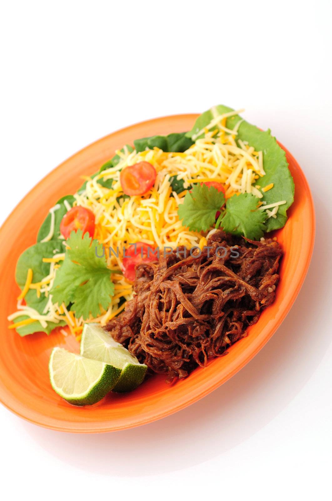 Shredded barbeque beef on an orange plate with a healthy salad