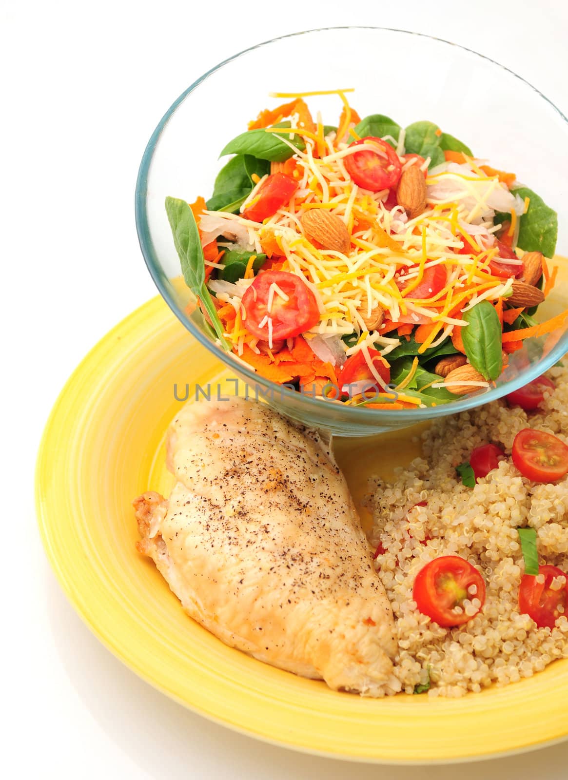 A healthy lunch on a yellow plate with chicken quinoa and a salad