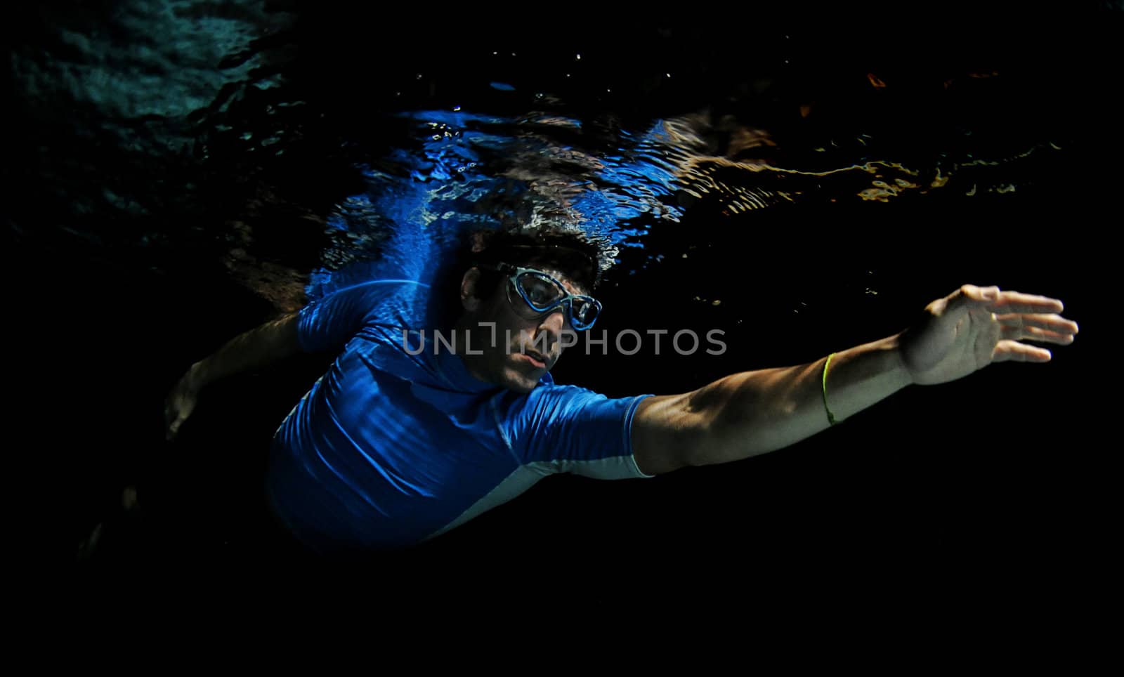 Man swimming underwater in dark pool for exercise